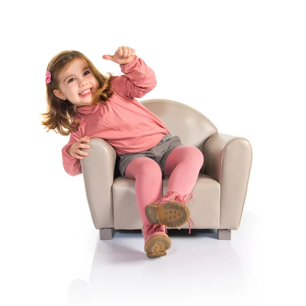 Petite fille assise sur un fauteuil avec le pouce levé — Photo