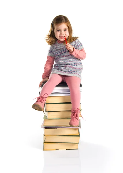 Meisje, zittend op boeken — Stockfoto