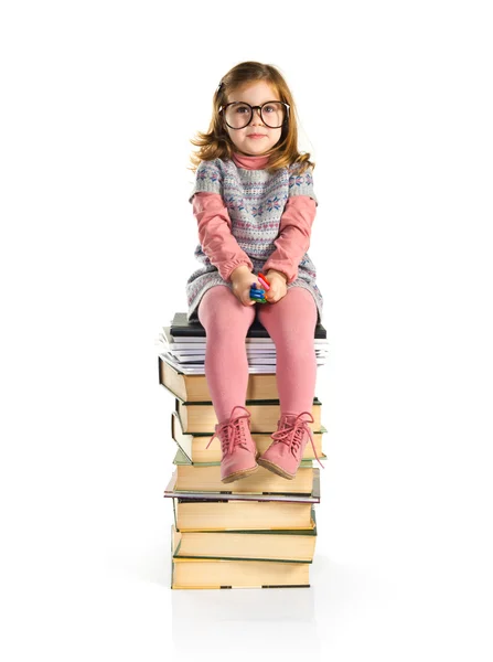 Kleines Mädchen mit Brille sitzt auf Büchern — Stockfoto