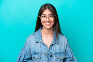 Güzel genç bir kadın mavi arka planda yalnız poz veriyor.    