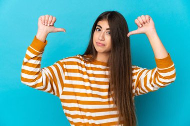 Mavi arka planda soyutlanmış, gururlu ve kendini beğenmiş beyaz bir kadın.