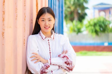 Dışarıdaki genç Çinli kadın kollarını ön cephede çapraz tutuyor.