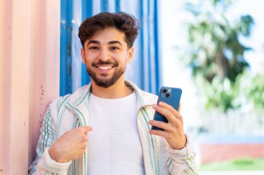 Yakışıklı bir Arap 'ın dışarıda cep telefonu kullanması sürpriz bir yüz ifadesi.