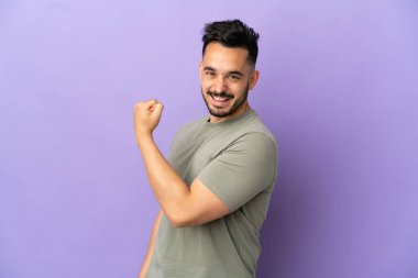 Mor arka planda izole edilmiş genç beyaz bir adam zaferi kutluyor.