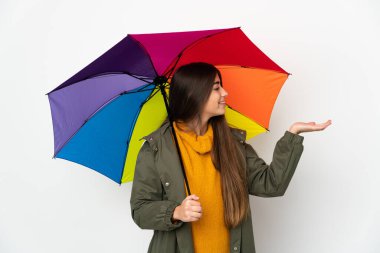 Beyaz arka planda izole edilmiş şemsiyeyi tutan genç bir kadın davet edilmek için ellerini yana uzatıyor.