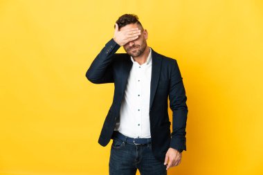 İzole edilmiş sarı arka planda, gözleri elleriyle kapatan bir iş adamı. Bir şey görmek istemiyorum.