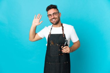 Önlüklü berber mutlu bir ifadeyle selamlıyor.