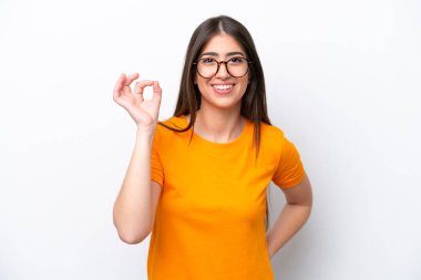 Beyaz arka planda izole edilmiş genç beyaz kadın parmaklarıyla tamam işareti gösteriyor.