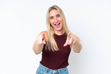 Beyaz arka planda izole edilmiş genç beyaz kadın şaşırmış ve ön tarafı işaret ediyor.