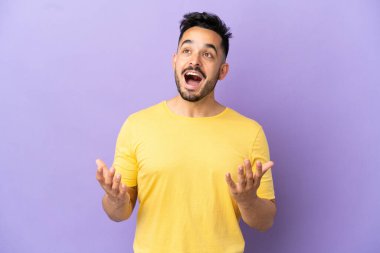 Mor arka planda yüzü sürpriz bir ifadeyle izole edilmiş genç beyaz bir adam.