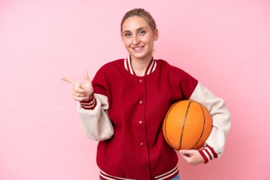 Pembe arka planda izole edilmiş beyaz tenli genç bir bayan parmak kenarı işaret ediyor.