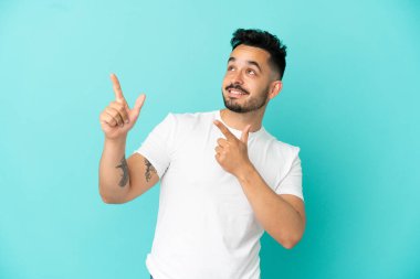 Mavi arka planda izole edilmiş genç beyaz adam işaret parmağıyla işaret etmek harika bir fikir.