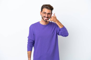 Beyaz arka planda izole edilmiş genç beyaz bir adam telefon jesti yapıyor. Bana geri dönüş işareti ver.