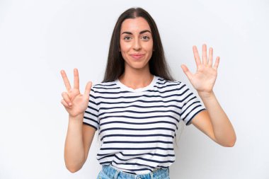 Beyaz arka planda izole edilmiş genç beyaz kadın parmaklarıyla sekizi sayıyor.