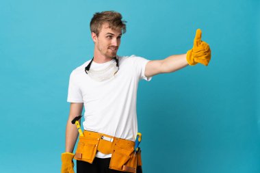 Genç elektrikçi, izole edilmiş duvarın üzerinden baş parmak işareti yapıyor.