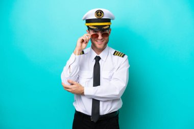 Kafkasyalı uçak pilotu mavi arka planda gözlüklü ve mutlu