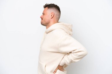 Beyaz arka planda yaşayan beyaz tenli yakışıklı genç adam gayret gösterdiği için sırt ağrısı çekiyor.