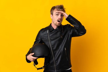 Sarı arka planda izole edilmiş motosiklet kasklı bir adam yan tarafa bakarken sürpriz jest yapıyor.