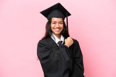 Üniversiteden mezun genç bir Kolombiyalı kadın pembe arka planda zaferi kutluyor.