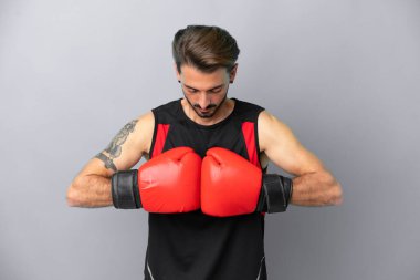 Gri arka planda boks eldivenli, beyaz, genç bir adam.
