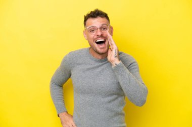 Sarı arka planda izole edilmiş, ağzı açık genç beyaz adam bağırıyor.