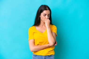 Kafkasyalı genç bir kadın mavi arka planda izole edilmiş. Şüpheleri var.