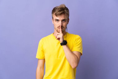 Mor arka planda izole edilmiş genç yakışıklı sarışın adam sessiz bir jest işareti gösteriyor. Parmağını ağzına sokuyor.