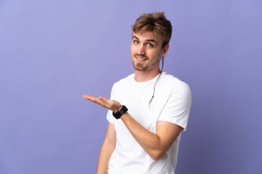 Mor arka planda soyutlanmış yakışıklı sarışın bir adam gülümserken bir fikir sunuyor.