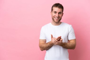 Pembe arka planda izole edilmiş genç beyaz adam gülüyor.