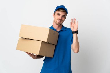 Genç teslimatçı sarışın adam beyaz arka planda izole edilmiş, mutlu bir ifadeyle selamlanıyor.