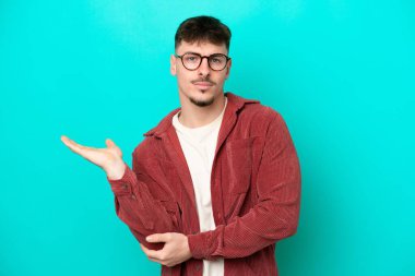 Kafkasyalı yakışıklı genç adam mavi arka planda izole edilmiş şüpheleri var.