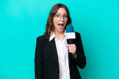 Genç TV sunucusu kadın, mavi arka planda mahsur kalmış, şaşırmış bir yüz ifadesi var.