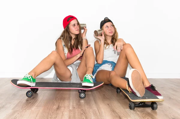 Друзья со скейтбордами разговаривают через жестяной телефон — стоковое фото