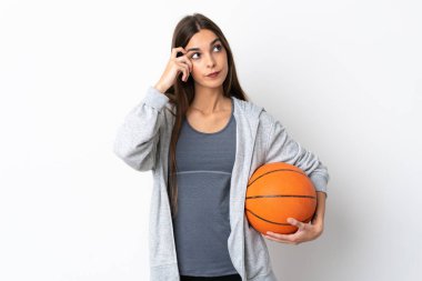 Basketbol oynayan genç bir kadın beyaz arka planda izole edilmiş. Şüpheleri ve düşünceleri var.