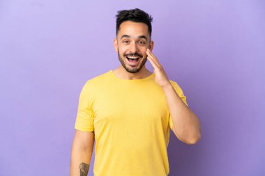 Mor arka planda izole edilmiş, şaşırmış ve şok olmuş yüzü olan genç beyaz bir adam.