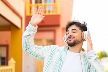 Açık havada müzik dinleyen ve dans eden yakışıklı bir Arap.