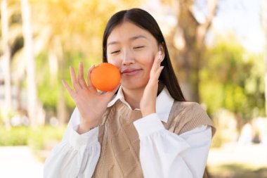 Açık havada elinde portakal tutan güzel bir Çinli kadın.