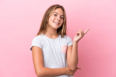Pembe arka planda izole edilmiş küçük beyaz kız mutlu ve yukarıya bakıyor.