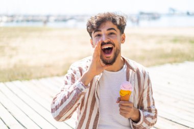 Ağzı açık bağıran, kornet dondurmalı yakışıklı bir Arap.