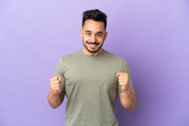 Mor arka planda izole edilmiş genç beyaz adam galibiyeti kutluyor.