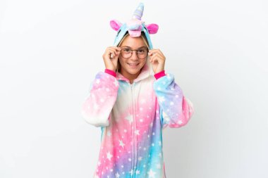 Beyaz arka planda gözlüklü ve şaşırmış tek boynuzlu at pijamalı küçük bir kız.