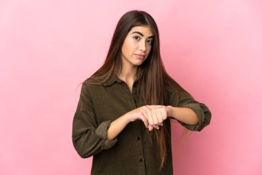 Pembe arka planda izole edilmiş beyaz bir kadın geç kalma jesti yapıyor.