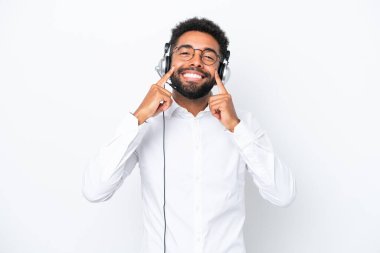 Telemarketer Brazilian man working with a headset isolated on white background smiling with a happy and pleasant expression