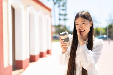 Güzel bir Çinli kadın açık havada kahve alıp bir şeyler fısıldıyor.