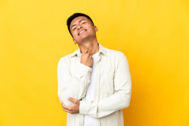 Genç Ekvadorlu adam sarı arka planda izole edilmiş gülüyor.