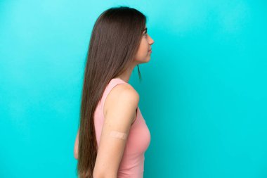 Arka planda mavi arka planda yara bandı olan beyaz bir kadın var.