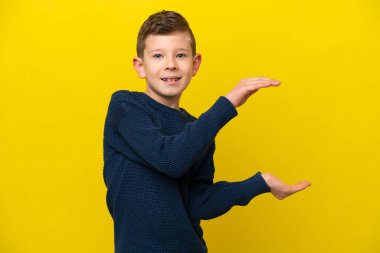 Sarı arka planda izole edilmiş beyaz bir çocuk ilan vermek için kopyalama alanı tutuyor.