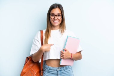 Mavi arka planda yalıtılmış genç bir bayan öğrenci.