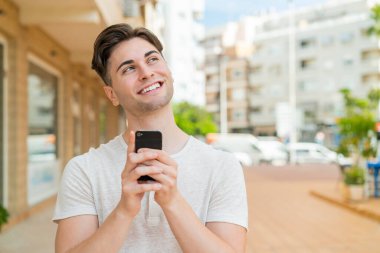 Genç ve yakışıklı bir adam cep telefonu kullanıyor.