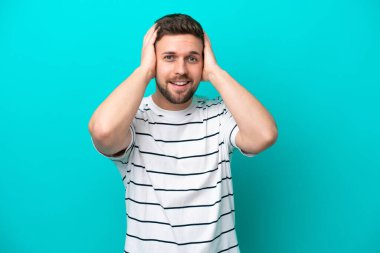 Kafkasyalı genç adam mavi arka planda tek başına gülüyor.